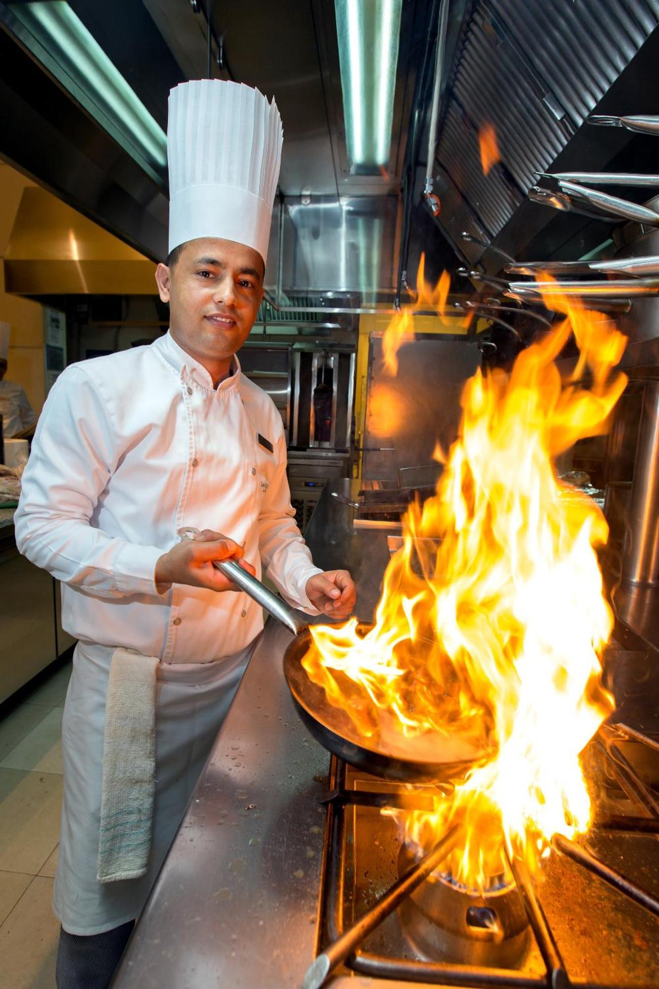 La Cigale Hotel Managed By Accor Доха Екстер'єр фото A chef cooking with a flaming skillet